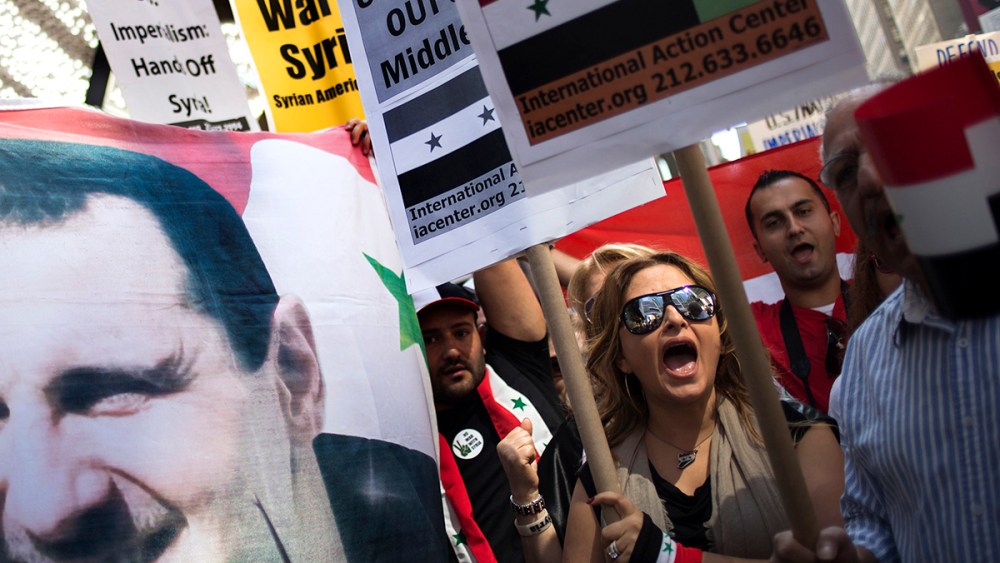 Claudia Salmeh, a Syrian born American who supports President Bashar al-Assad, chants "No More War," as fellow activists hold an image of Assad during an anti-war rally in Times Square, New York