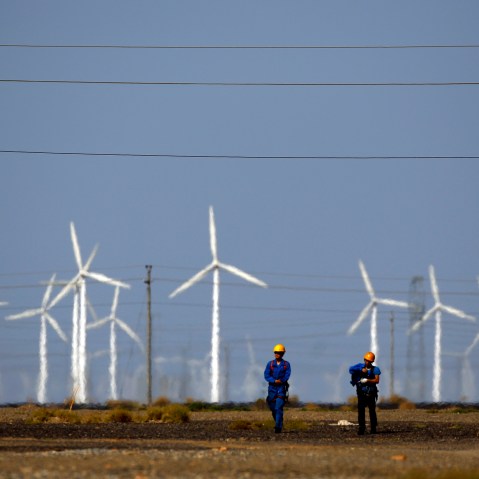 Workers walk near wind turbines for generating electricity, at a wind farm in Guazhou, 950km (590 miles) northwest of Lanzhou, Gansu Province, Sep. 15, 2013. (Photo by Carlos Barria/Reuters)