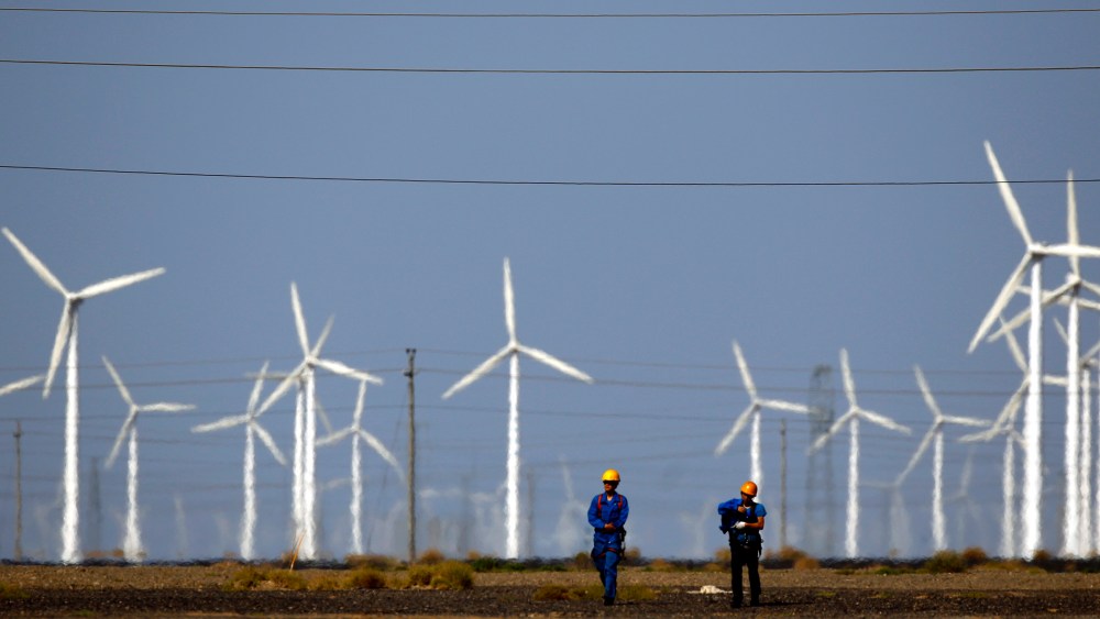 Workers walk near wind turbines for generating electricity, at a wind farm in Guazhou, 950km (590 miles) northwest of Lanzhou, Gansu Province, Sep. 15, 2013. (Photo by Carlos Barria/Reuters)
