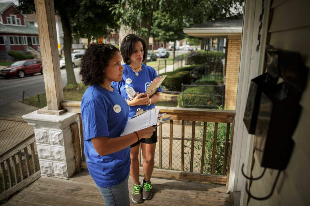 Get Covered America volunteers wait on a porch as they try to talk with one of the residents about the Affordable Care Act in Chicago, September 7, 2013.