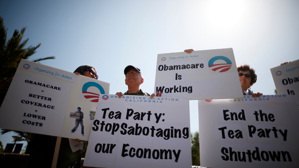 Demonstrators hold up signs at an education and awareness event on the Affordable Care Act and protest against Tea Party officials they say are threatening an economic shutdown, in Santa Monica, Calif. on Oct. 10, 2013.