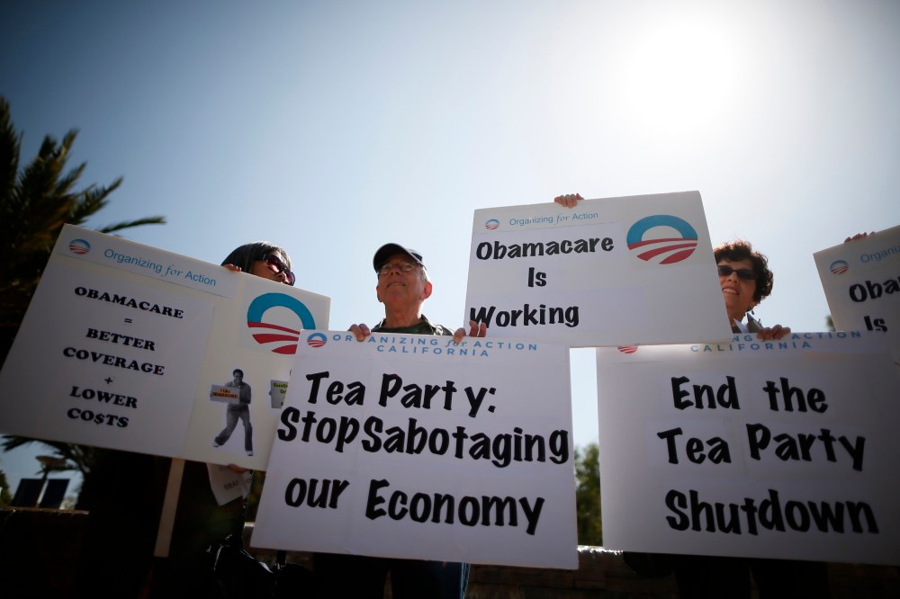 Demonstrators hold up signs at an education and awareness event on the Affordable Care Act and protest against Tea Party officials they say are threatening an economic shutdown, in Santa Monica, Calif. on Oct. 10, 2013.