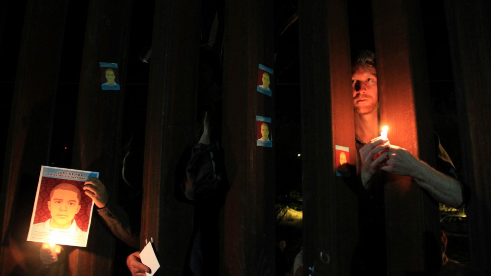 Activists hold candles and pictures of late Mexican youth Jose Antonio Elena Rodriguez through the border fence between Mexico and the U.S. in Nogales, Oct. 10, 2013. (Photo by Stringer/Reuters)