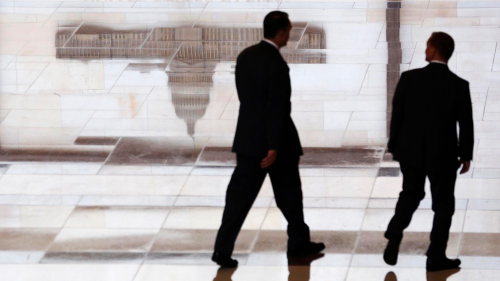 Men walk past a reflected image of the Capitol inside the U.S. Capitol Visitors Center in Washington  October 16, 2013.