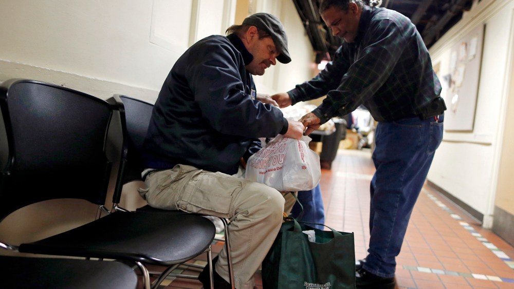 Food pantry handler Kenneth Willis (R) hands out bags of food to Frank Doyle at the Emergency Assistance Program at the Chicago Catholic Charities in Chicago on Nov. 1, 2013