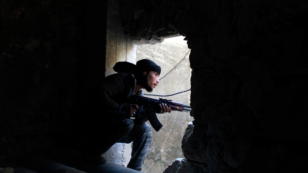 A Free Syrian Army fighter kneels with his weapon in Aleppo's Karm al-Jabal district