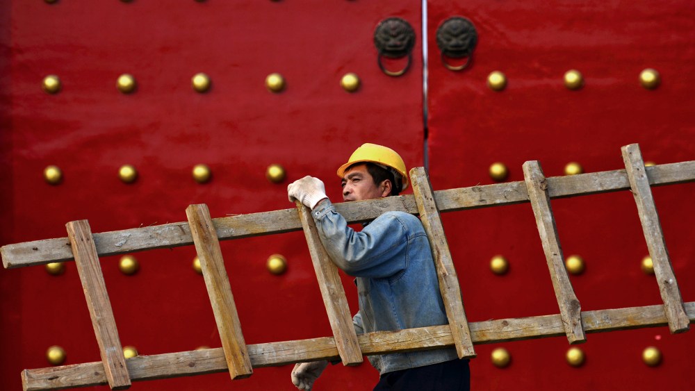 A worker carrying a ladder walks past a palace used by ancient emperors in Shenyang