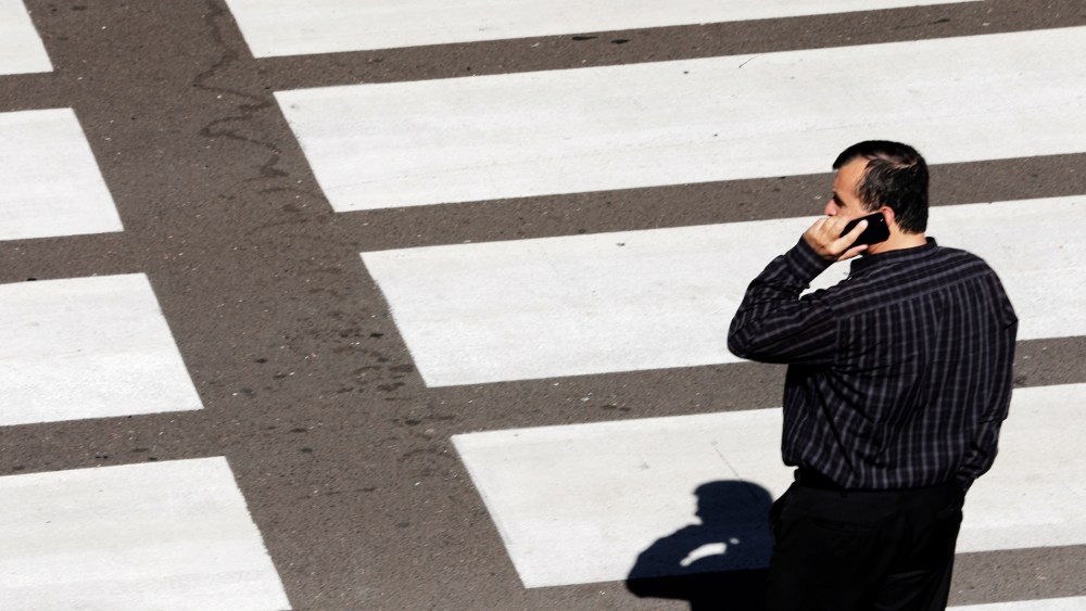 A man talks on his mobile phone as he waits at a crosswalk at Lindbergh Field Airport in San Diego