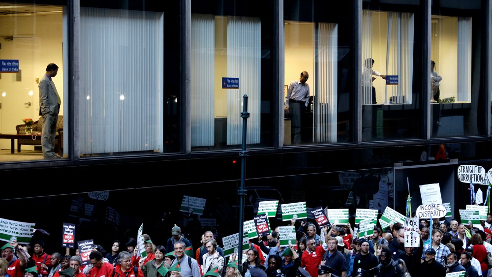 Bankers from Bank of India watch from a window as Occupy Wall Street protesters march 47th Street in New York Sept. 17, 2013