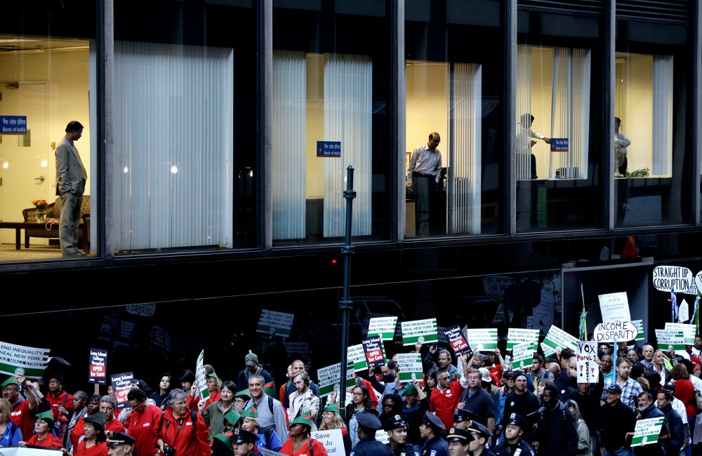 Bankers from Bank of India watch from a window as Occupy Wall Street protesters march 47th Street in New York Sept. 17, 2013