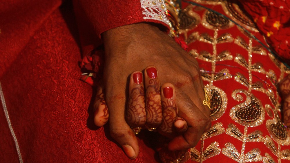 A bride and groom hold hands as they sit together during a mass marriage ceremony held in Karachi, Nov. 30, 2013. (Photo by Athar Hussain/Reuters)