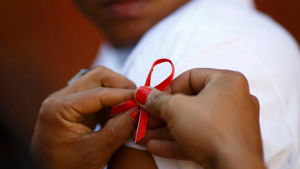 A red ribbon is put on the sleeves of a man by his friend to show support for people living with HIV during a program to raise awareness about AIDS on World AIDS Day in Kathmandu on Dec. 1, 2013. (Photo by Navesh Chitrakar/Reuters)
