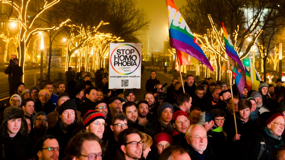 People hold a placard and rainbow flags as they call on the Russian authorities to lift anti-gay laws ahead of the Sochi 2014 Olympics during a protest outside the Russian embassy in Berlin, Dec. 12, 2013.