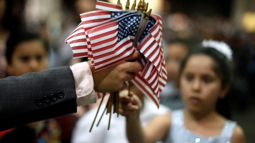 A man hands out U.S. flags at a naturalization ceremony for new U.S. citizens in Los Angeles