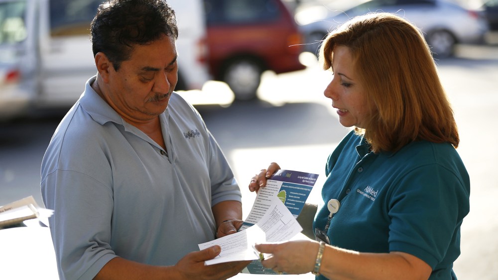 Engrith Acosta, patient care coordinator at AltaMed, speaks to a man during a community outreach on Obamacare in Los Angeles, Calif., Nov. 6, 2013.