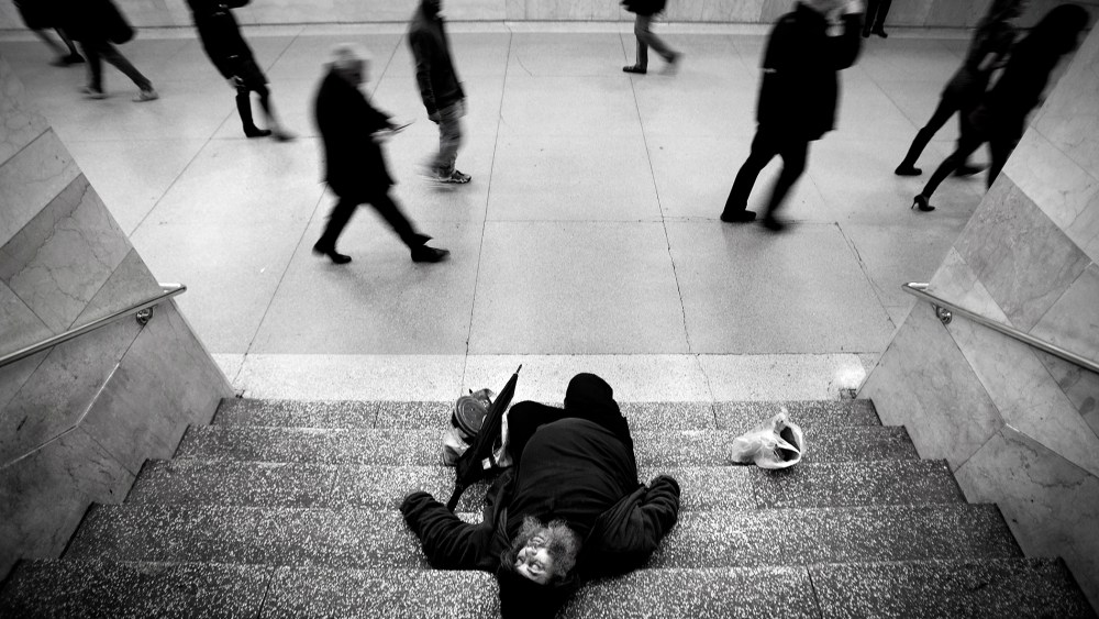 A man sleeps on the stairs of Grand Central Station as commuters pass by on Christmas Eve in New York, Dec. 24, 2013.