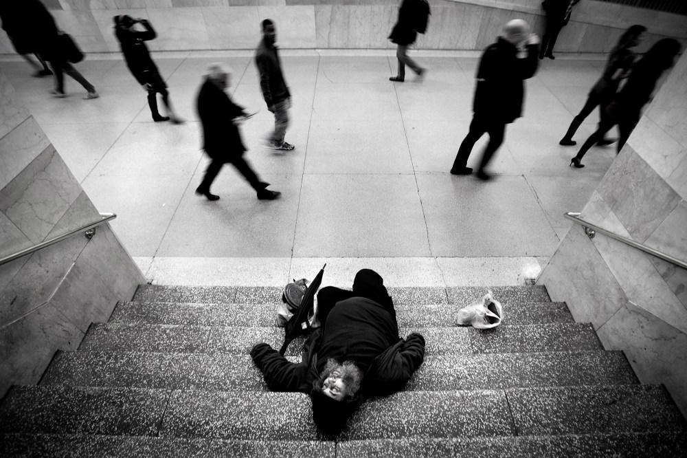 A man sleeps on the stairs of Grand Central Station as commuters pass by on Christmas Eve in New York, Dec. 24, 2013.