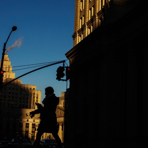 A woman crosses the street as the setting sun illuminates buildings behind her in New York, N.Y. (Photo by Lucas Jackson/Reuters)