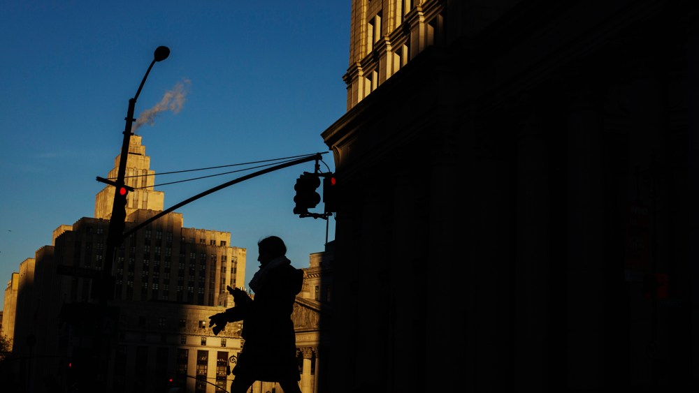 A woman crosses the street as the setting sun illuminates buildings behind her in New York, N.Y. (Photo by Lucas Jackson/Reuters)