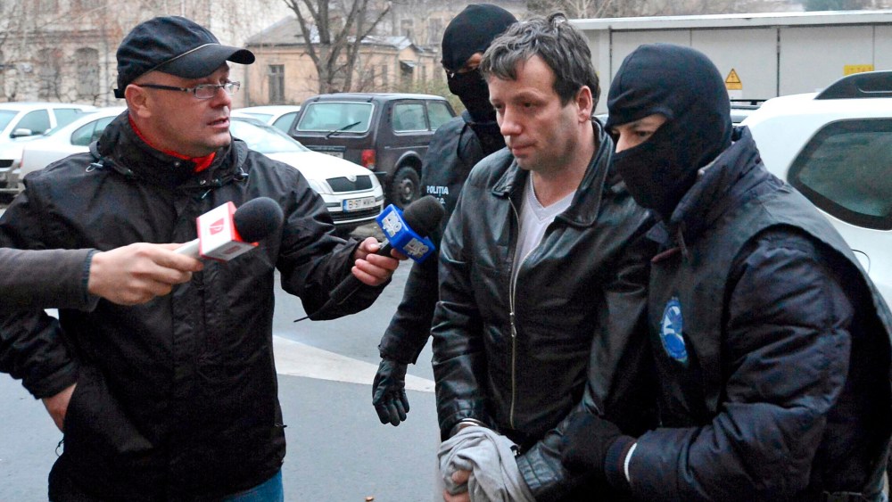 Marcel Lazar Lehel, 40, is escorted by masked policemen in Bucharest, after being arrested in Arad, 550 km (337 miles) west of Bucharest, Jan.22, 2014. (Photo by Silviu Matei/Mediafax/Reuters)
