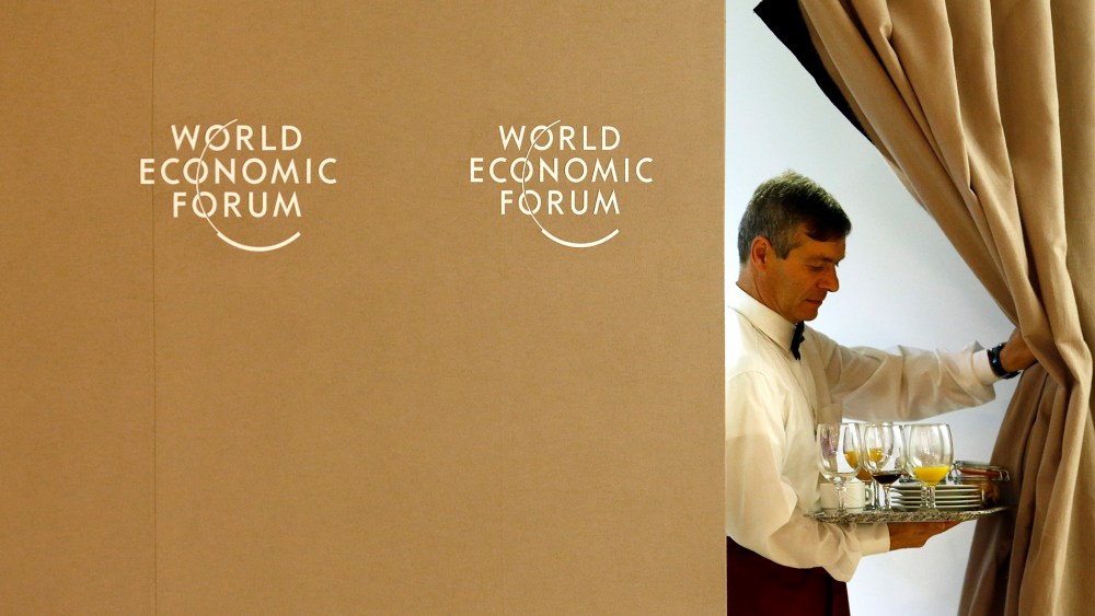 A waiter pulls back a curtain during World Economic Forum in Davos
