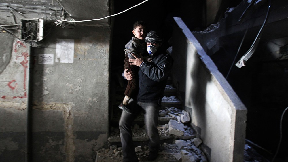 A man wearing a mask holds a child who was rescued at a site hit by what activists said were barrel bombs dropped by government forces, Jan. 31, 2014, in the Al-Ansari neighborhood of Aleppo, Syria.