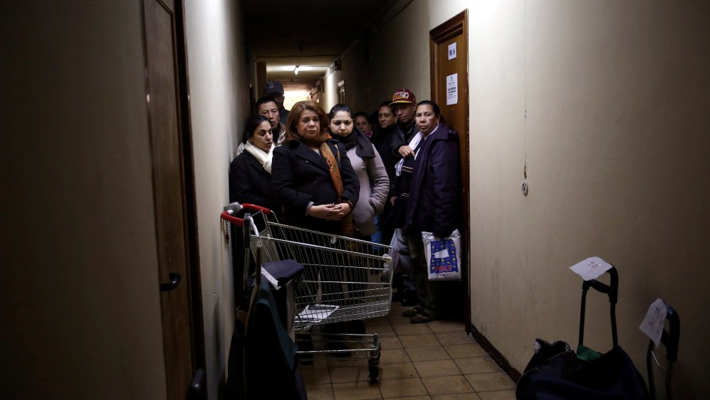 Food bank recipients wait for their cart numbers to be called out to pick up their donated food on distribution day at Madrid's Tetuan food bank in Madrid, Spain on Dec. 10, 2013.