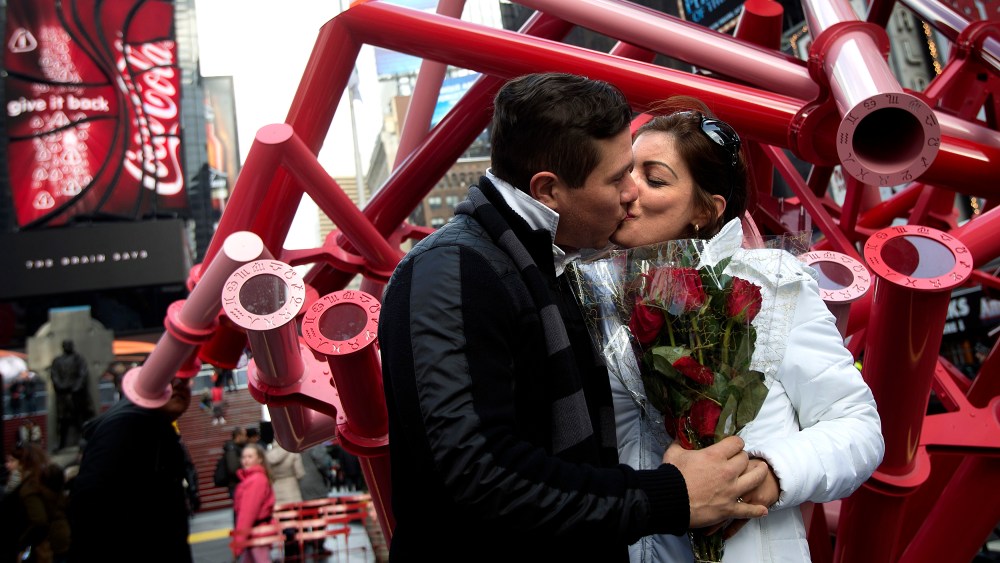 A couple, holding roses, kiss in Times Square on Valentine's Day in New York Feb. 14, 2014. (Photo by Carlo Allegri/Reuters)