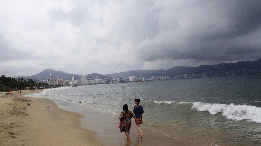 Tourists walk along a beach as dark clouds brought by hurricane Blanca are seen in Acapulco, state of Guerrero, on June 4, 2015. (Photo by Claudio Vargas/Stringer Mexico/Reuters)