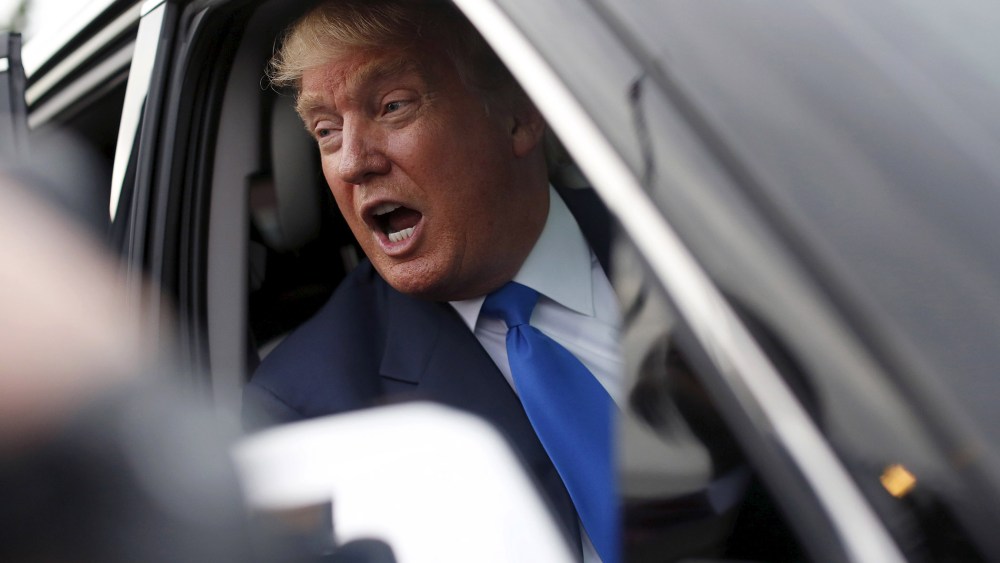 Republican presidential candidate Trump speaks to the media through his SUV window after a rally in Manchester