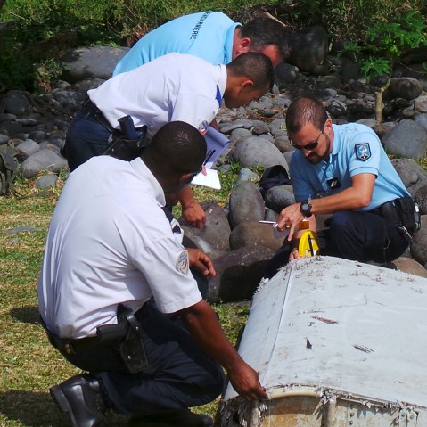 French gendarmes and police inspect a large piece of plane debris which was found on the beach in Saint-Andre, on the French Indian Ocean island of La Reunion, July 29, 2015. (Photo by Zinfos974/Prisca Bigot TPX/Reuters)