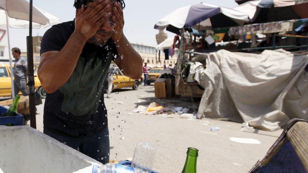 A man washes his face to cool off during a warm summer day in Baghdad (Photo by Ahmed Saad/Reuters).