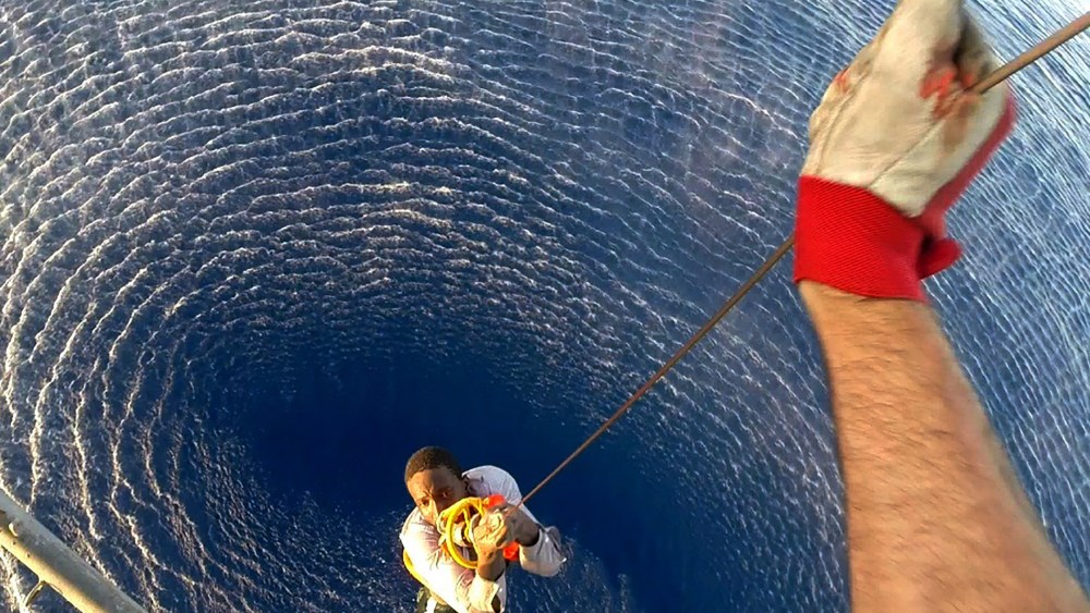 A migrant is rescued by an Italian Navy helicopter in the area where his boat sank in the Mediterranean Sea, Aug. 11, 2015. (Photo courtesy of the Italian Navy/Reuters)