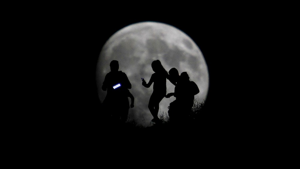 A group of hikers are seen silhouetted against the moon in Tijuana, Mexico, Aug. 27, 2015. (Photo by Jorge Duenes/Reuters)