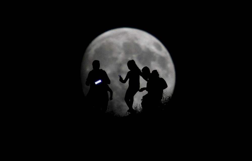 A group of hikers are seen silhouetted against the moon in Tijuana, Mexico, Aug. 27, 2015. (Photo by Jorge Duenes/Reuters)