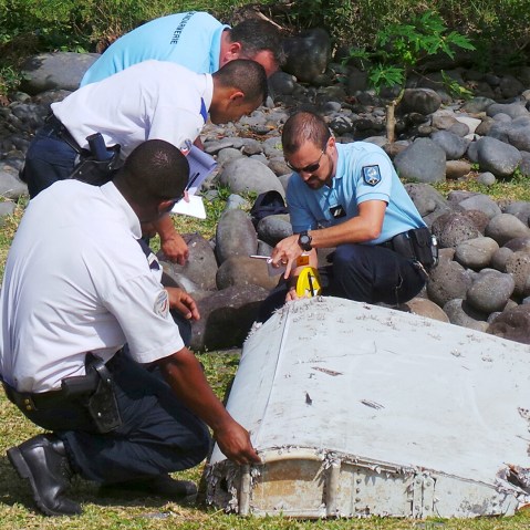 French gendarmes and police inspect a large piece of plane debris which was found on the beach in Saint-Andre, on the French Indian Ocean island of La Reunion, July 29, 2015. (Photo by Prisca Bigot/Zinfos974/Reuters)