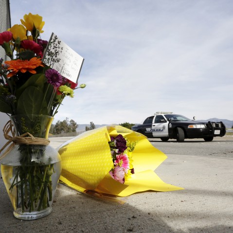 A San Bernardino police officer stands near flowers left near the scene of Wedneday's shooting rampage, at the Inland Regional Center, in San Bernardino, Calif., Dec. 3, 2015. (Photo by Jonathan Alcorn/Reuters)