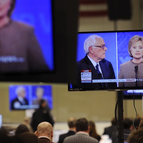 Democratic presidential candidates Hillary Clinton and Bernie Sanders appear on screens in the media room during the debate held at Saint Anselm College in Manchester, N.H., Dec. 19, 2015. (Photo by Gretchen Ertl/Reuters)