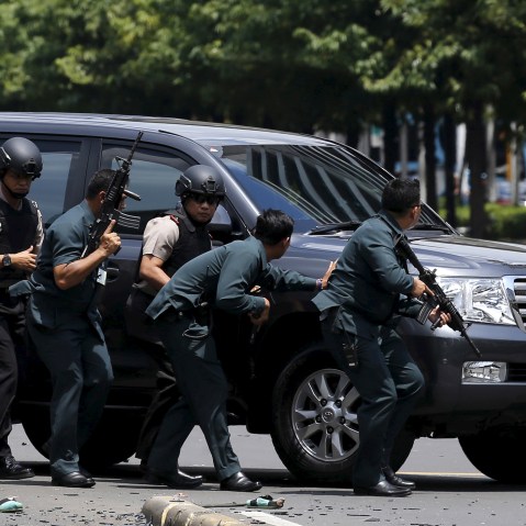 Indonesian police hold rifles while walking behind a car for protection in Jakarta on Jan. 14, 2016. (Photo by Beawiharta Beawiharta/Reuters)