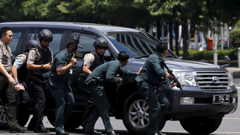 Indonesian police hold rifles while walking behind a car for protection in Jakarta on Jan. 14, 2016. (Photo by Beawiharta Beawiharta/Reuters)