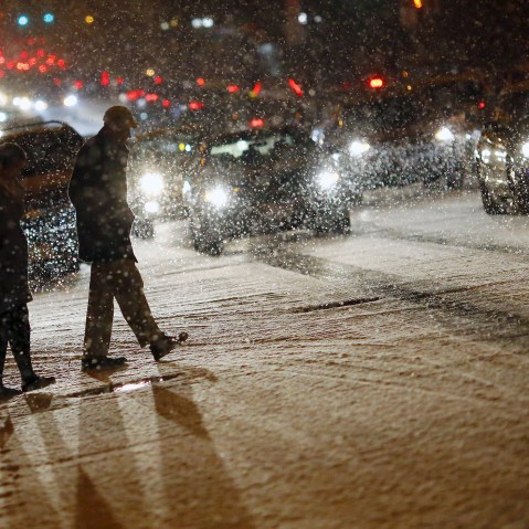 People cross a street as it snows in Washington, Jan. 20, 2016. (Photo by Carlos Barria/Reuters)