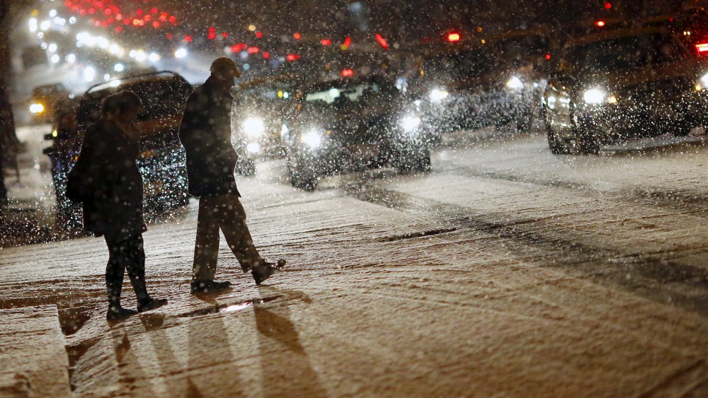 People cross a street as it snows in Washington, Jan. 20, 2016. (Photo by Carlos Barria/Reuters)
