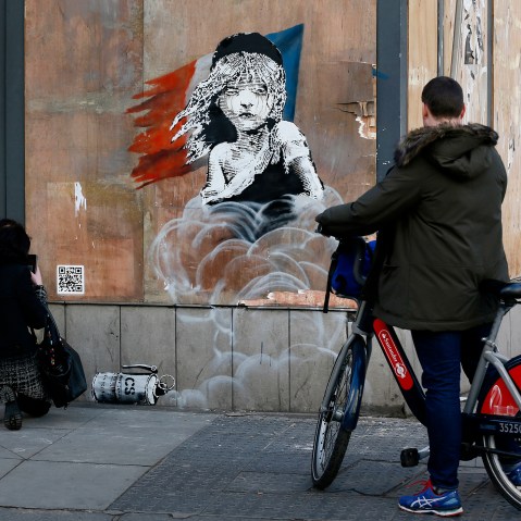 People photograph a new graffiti mural attributed to Banksy, opposite the French embassy in London, Jan. 25, 2016. (Photo by Stefan Wermuth/Reuters)