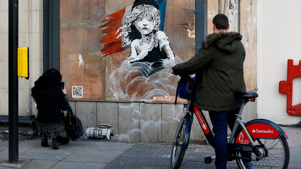 People photograph a new graffiti mural attributed to Banksy, opposite the French embassy in London, Jan. 25, 2016. (Photo by Stefan Wermuth/Reuters)