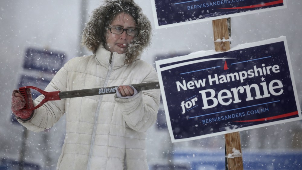 A worker uses a shovel to wipe snow off of an election sign in Manchester, N.H., Feb. 5, 2016. (Photo by Carlo Allegri/Reuters)