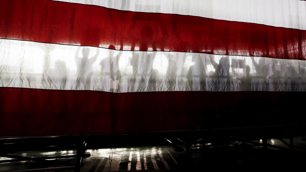 Supporters of Democratic presidential candidate Bernie Sanders are seen in silhouette behind the U.S. flag during a rally in Charlotte, N.C., March 14, 2016. (Photo by Shannon Stapleton/Reuters)