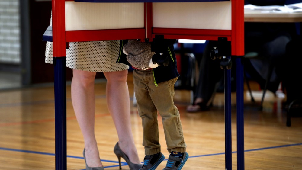 A woman fills out her ballot in a voting booth in the New York, in the U.S. presidential primary election, as her young son looks on, Grafflin School in Chappaqua, N.Y., April 19, 2016. (Photo by Mike Segar/Reuters)