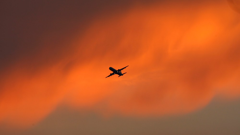 A passenger aircraft flies against the backdrop of monsoon clouds in New Delhi
