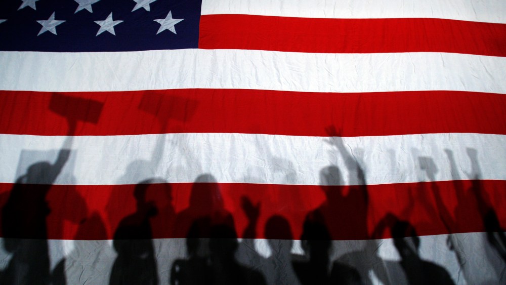 Supporters cast shadows on a U.S. flag as they cheer during a campaign rally.