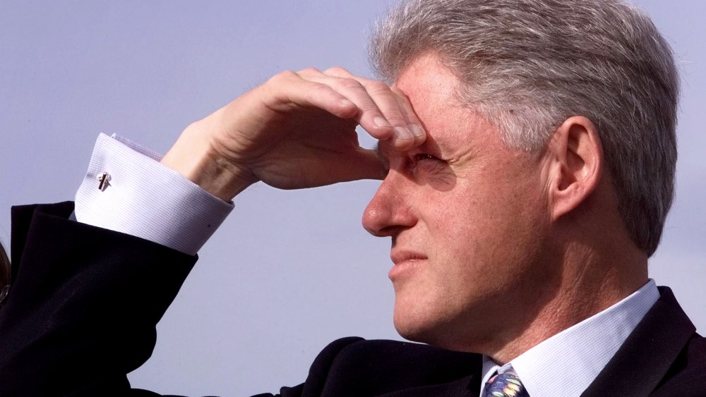 U.S. President Bill Clinton shades his eyes as he waits to be introduced at an event in Newport, R.I. in 1998.